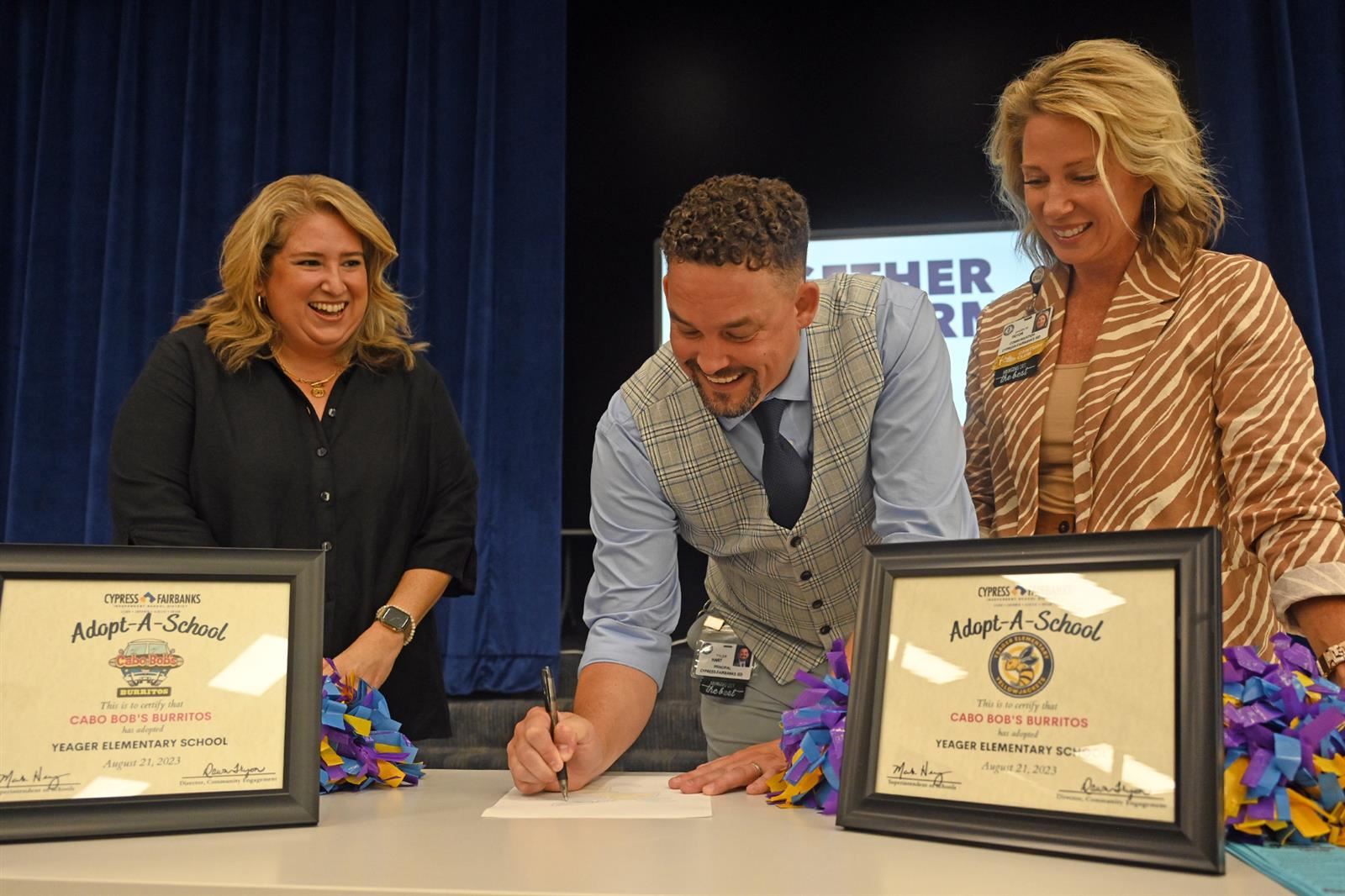 Tyler Hart, Yeager Elementary School principal, signs an Adopt-a-School partnership agreement.